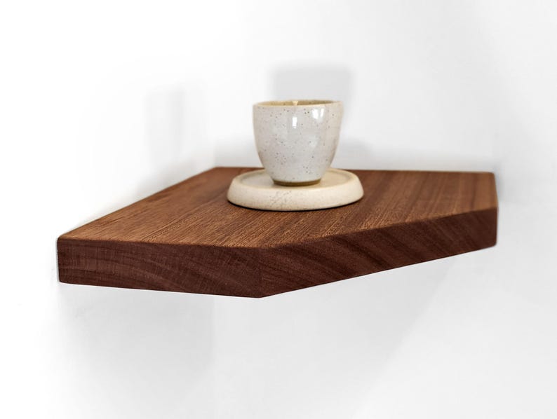 Side view of a mahogany corner floating shelf displaying a candle.