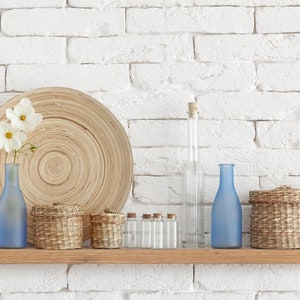 Thick oak floating shelf on a white brick wall with decorative items on the long shelf