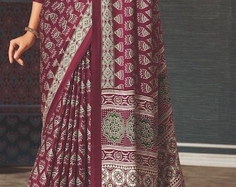 May include: A maroon silk saree with a white and green floral print. The saree has a border with a geometric pattern.