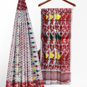 May include: A white and red patterned saree with yellow and green accents. The saree is draped over a hanger.