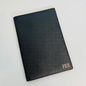 May include: Black leather passport holder with gold lettering that says "FEE".