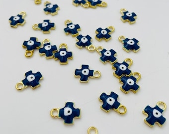 May include: A collection of gold-toned charms with a blue and white evil eye design. The charms are shaped like a cross and have a loop at the top for attaching to jewelry.