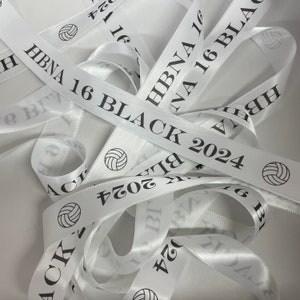 May include: White satin ribbon with black text that reads "HBNA 16 BLACK 2024" and a volleyball graphic.