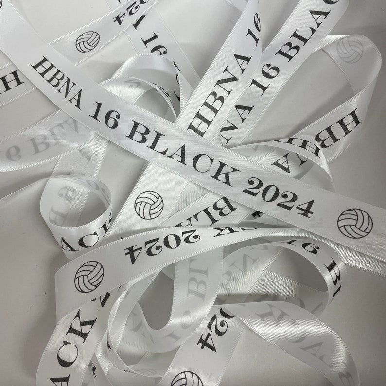 May include: White satin ribbon with black text that reads "HBNA 16 BLACK 2024" and a volleyball graphic.