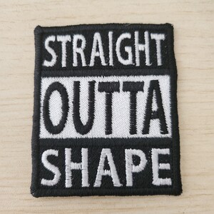 Op de afbeelding: Zwarte geborduurde patch met witte tekst die "STRAIGHT OUTTA SHAPE" luidt.