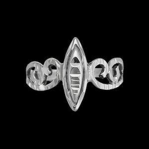 May include: A silver ring with a decorative, ornate design. The ring features a central oval-shaped piece with a textured surface and intricate details.