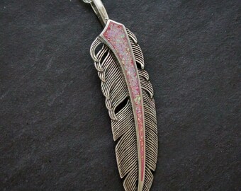 Könnte beinhalten: Eine silberne Federnkette mit einem Anhänger aus rosa Opal. Die Feder ist mit Linien verziert und hat eine zarte Kette.
