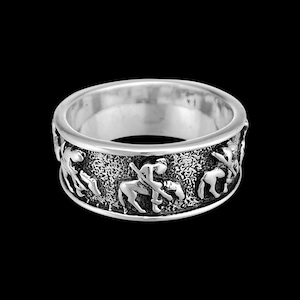 May include: A silver ring with a detailed design of figures on horseback. The ring is a wide band with a textured surface.