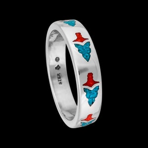Op de afbeelding: Een zilveren bandring met turquoise en rode inleg. De ring heeft een herhalend patroon van pijlpunten.