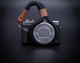 Op de afbeelding: Een zilveren Canon camera met een zwarte lens en een zwart-bruine band. De camera heeft de tekst "Canon Zoom Lens 4.2x IS" op de lens.