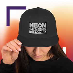 May include: A black baseball cap with a flat peak, featuring the embroidered text "NEON GENESIS HARDCORE" in silver. The cap is a classic style, suitable for everyday wear and has a structured fit.