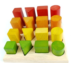 Op de afbeelding: Een houten vormsorteerspeelgoed met een lichte houten basis. De sorteerder heeft verschillende felgekleurde geometrische vormen, waaronder kubussen, driehoeken en cilinders in rood, oranje, geel en groen. De vormen zijn ontworpen om in bijbehorende gaten te passen.