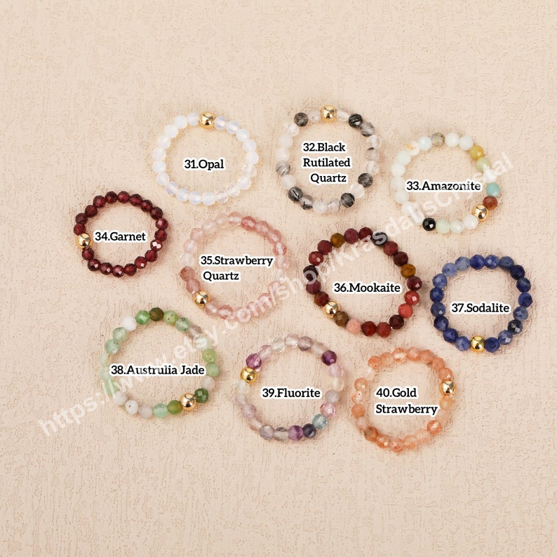 Peut inclure: Dix bracelets en pierres pr&eacute;cieuses avec des perles dor&eacute;es. Chaque bracelet est fait avec un type de pierre pr&eacute;cieuse diff&eacute;rent, y compris l'opale, le grenat, le quartz fraise, le quartz rutil&eacute; noir, l'amazonite, la mookaite, la sodalite, le jade d'Australie, la fluorine et la fraise dor&eacute;e.