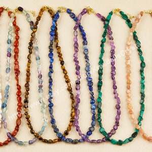 Puede incluir: Nueve collares de piedras preciosas con cierres de oro. Los collares están hechos de varias piedras, incluyendo rojo, naranja, azul, morado, verde y rosa.