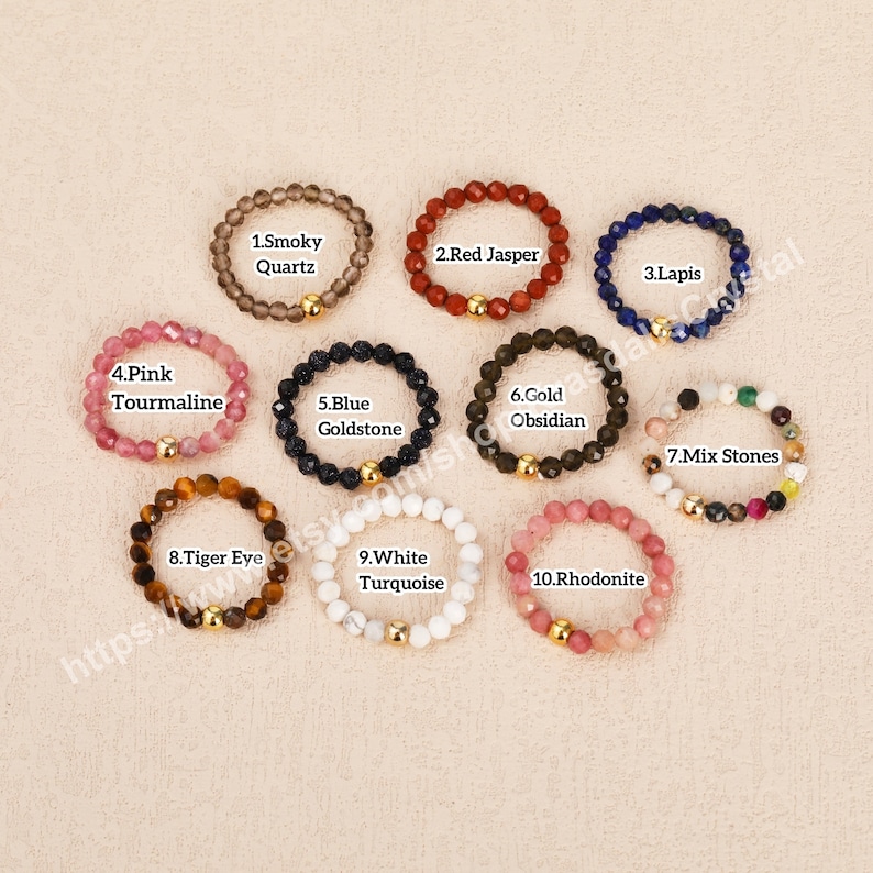 Peut inclure: Dix bracelets en pierres pr&eacute;cieuses avec des perles dor&eacute;es. Les bracelets sont dispos&eacute;s en cercle sur un fond beige. Les pierres pr&eacute;cieuses comprennent le quartz fum&eacute;, le jaspe rouge, le lapis-lazuli, la tourmaline rose, la goldstone bleue, l'obsidienne dor&eacute;e, des pierres m&eacute;lang&eacute;es, l'&oelig;il de tigre, la turquoise blanche et la rhodonite.