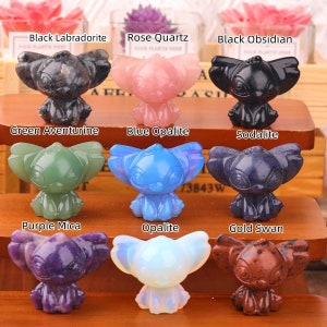 Op de afbeelding: Negen kleine, handgesneden kristalfiguurtjes van een cartoonfiguur, elk figuurtje is van een ander kristal in een andere kleur. De kristallen zijn: Zwarte Labradoriet, Roze Kwarts, Zwarte Obsidiaan, Groene Aventurijn, Blauwe Opaliet, Sodalite, Paarse Mica, Opaliet en Gouden Zwaan.