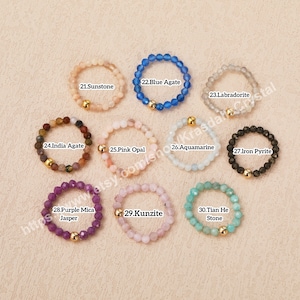 Peut inclure: Dix bagues en pierres pr&eacute;cieuses diff&eacute;rentes avec des accents dor&eacute;s. Les bagues sont dispos&eacute;es en deux rang&eacute;es de cinq. Les pierres pr&eacute;cieuses sont&nbsp;: pierre de soleil, agate bleue, labradorite, agate d&rsquo;Inde, opale rose, aigue-marine, pyrite de fer, jaspe mica violet, kunzite et pierre de tian he.