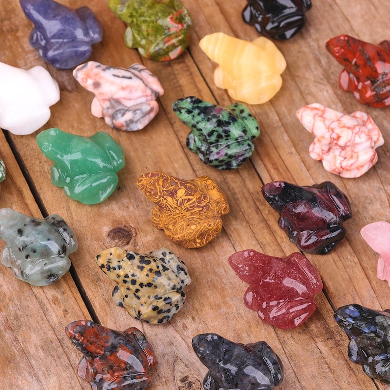 K&ouml;nnte beinhalten: Eine Sammlung von 16 kleinen, geschnitzten Froschfiguren aus verschiedenen Arten von poliertem Stein. Die Fr&ouml;sche sind in verschiedenen Farben, darunter Gr&uuml;n, Rot, Blau, Braun, Schwarz, Wei&szlig; und Pink.