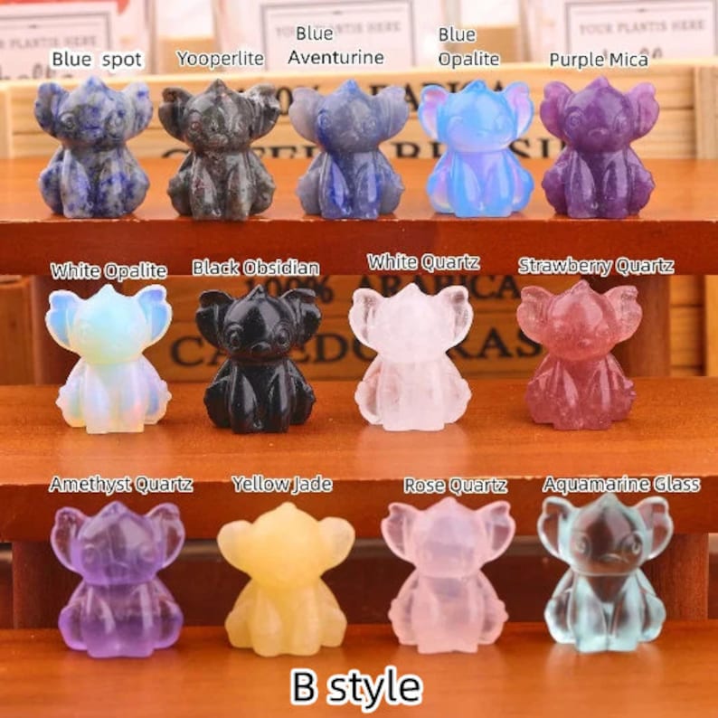 Op de afbeelding: Twaalf kleine, gegraveerde kristalfiguren van Stitch uit de Disney-film Lilo & Stitch. De figuren zijn gemaakt van verschillende soorten kristallen, waaronder blauwe aventurijn, witte opaal, zwarte obsidiaan en amethistkwarts. De figuren zijn gerangschikt in drie rijen van vier, met de namen van de kristallen boven elke rij.