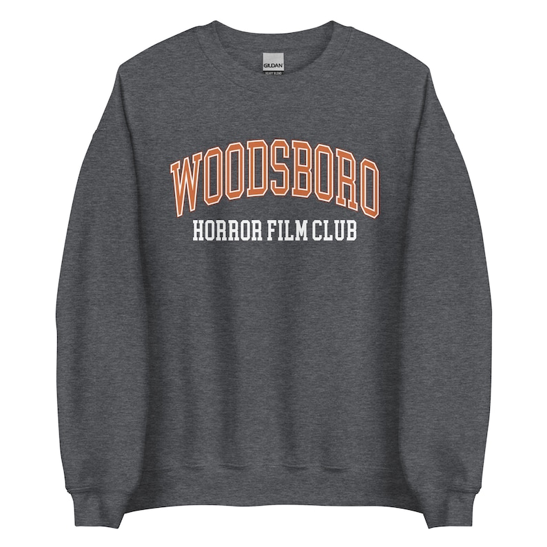 May include: Dark gray sweatshirt with the text "WOODSBORO HORROR FILM CLUB" in orange and white lettering.
