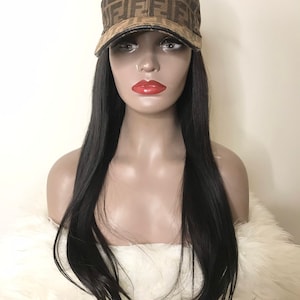 May include: A brown and tan baseball cap with a repeating logo pattern. The cap has a curved brim and is displayed on a mannequin head with long black hair.