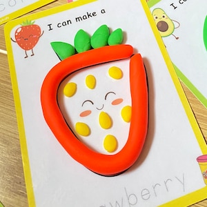 Puede incluir: Una tarjeta de actividad imprimible con un borde amarillo y el texto "Puedo hacer una fresa". La tarjeta muestra una fresa de plastilina roja con hojas verdes y semillas amarillas. El texto "fresa" est&aacute; escrito en l&iacute;neas punteadas debajo de la fresa.
