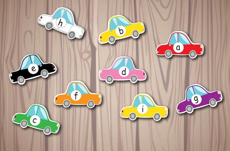 Puede incluir: Nueve coches de juguete, cada uno de un color diferente, con una letra del alfabeto en el parabrisas. Los coches est&aacute;n dispuestos en fila sobre un fondo de madera.
