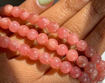 May include: A pink gemstone bracelet with round beads. The bracelet is made of natural stones and is a beautiful accessory for any occasion.