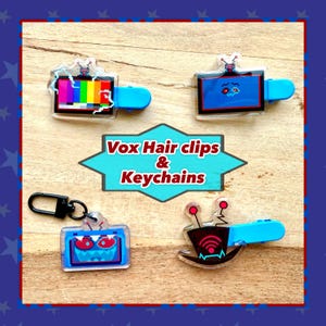 May include: Four acrylic hair clips and keychains with a retro TV theme. The hair clips and keychains have a blue handle and a variety of designs, including a TV test pattern, a sad face, a monster face, and a wifi signal. The text "Vox Hair clips & Keychains" is in the center.