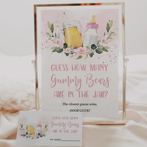 May include: A pink and white printable sign with a floral design and a beer mug and baby bottle. The sign says "Guess how many Gummy Bears are in the jar? The closest guess wins. Good luck!"