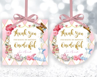 May include: Two pink and white Alice in Wonderland themed thank you tags. One is square and the other is round. Both feature a pink and white checkered background with gold accents. The text reads "Thank you for making my birthday Onederful".