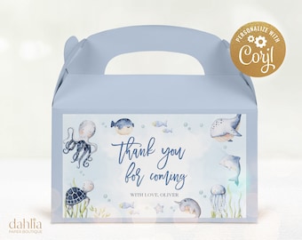 May include: Light blue favor box with a handle. The front of the box has a watercolor design of sea creatures, including an octopus, a pufferfish, a whale, a turtle, a dolphin, and a jellyfish. The text on the box reads "Thank you for coming with love, Oliver".