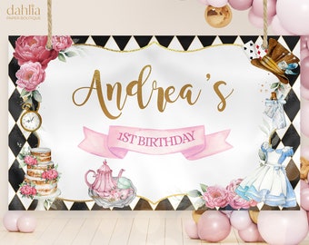 May include: A white Alice in Wonderland themed birthday banner with black and white diamond pattern border. The banner features gold lettering that says "Andrea's 1st Birthday" with a pink ribbon and watercolor illustrations of a teapot, teacups, a cake, flowers, and Alice in Wonderland characters.