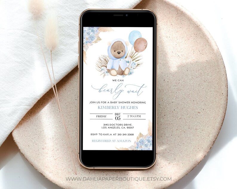 Pu&ograve; includere: Un invito a una festa di baby shower blu e marrone con un orsacchiotto che indossa un maglione con cappuccio blu e tiene dei palloncini. Il testo recita "We can barely wait" e include la data, l'ora e il luogo dell'evento. Sono incluse anche le informazioni RSVP.