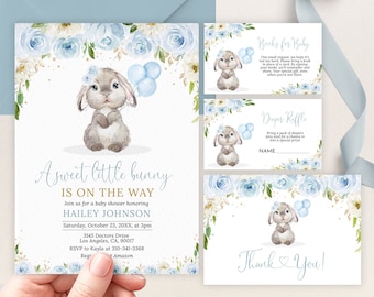 May include: A baby shower invitation featuring a watercolour illustration of a bunny holding blue balloons. The invitation is decorated with blue and white flowers and gold glitter. The text on the invitation reads "A sweet little bunny is on the way" and includes the baby's name, the date and time of the shower, and the address. There are also two smaller cards for "Books for Baby" and "Diaper Raffle".