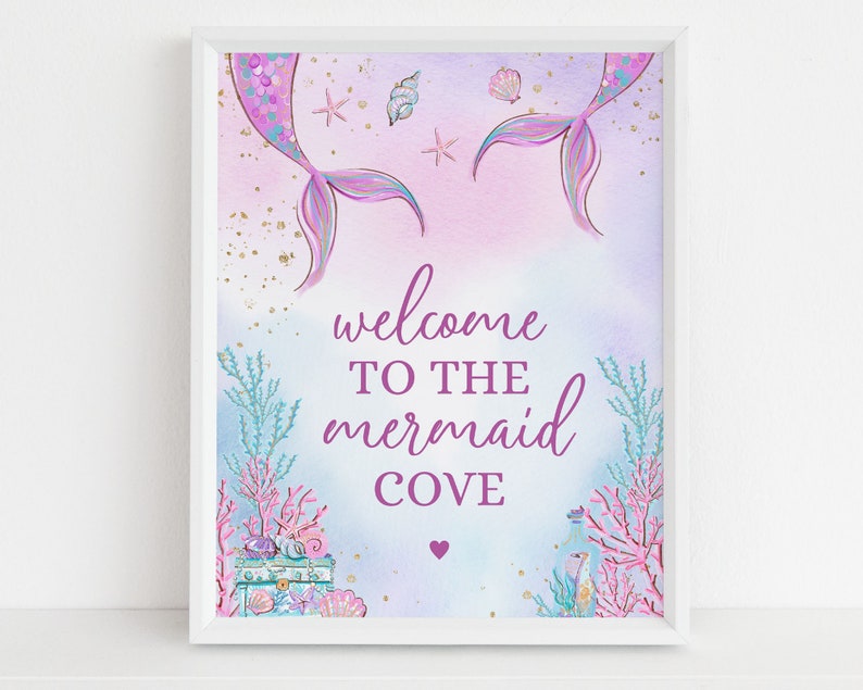 May include: A printable sign with a mermaid tail design in shades of purple and blue. The sign says "Welcome to the Mermaid Cove" with a small heart below the text.