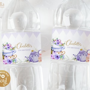 May include: Two clear plastic water bottles with purple and gold labels. The labels feature a teacup, teapot, and floral designs. The text on the labels reads "Charlotte's 5th Birthday".