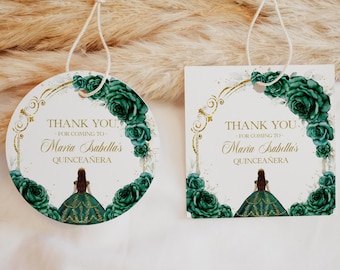 May include: Two round thank you tags with a green floral design and gold accents. The text on the tags reads "Thank You. For coming to Maria Isabella's Quinceañera".