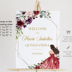 May include: A white welcome sign with gold glitter and a gold geometric frame. The sign features a watercolour floral design with burgundy, pink, and white flowers. The text reads "Welcome to Maria Isabella's Quincea&ntilde;era 12.05.2022".