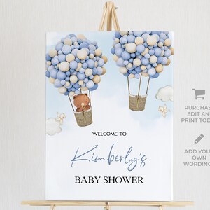 K&ouml;nnte beinhalten: Willkommen zur Babyparty von Kimberly Schild mit einem blauen und beigefarbenen Ballon-Hei&szlig;luftballon mit einem Teddyb&auml;ren im Korb. Das Schild ist auf wei&szlig;em Hintergrund.