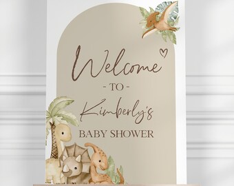 May include: Welcome to Kimberly's Baby Shower sign with a brown background and a watercolor illustration of dinosaurs and palm trees.