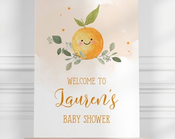 May include: Welcome to Lauren's Baby Shower sign with a watercolor illustration of a smiling orange with green leaves on a peach background.