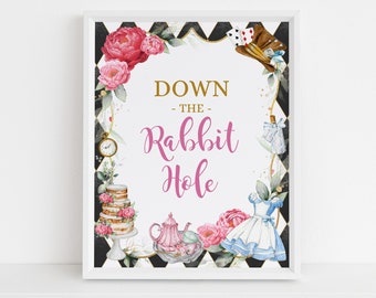 May include: A white sign with black and white checkered border and gold accents. The sign has a pink floral wreath with a pink and gold banner that says "Down the Rabbit Hole".