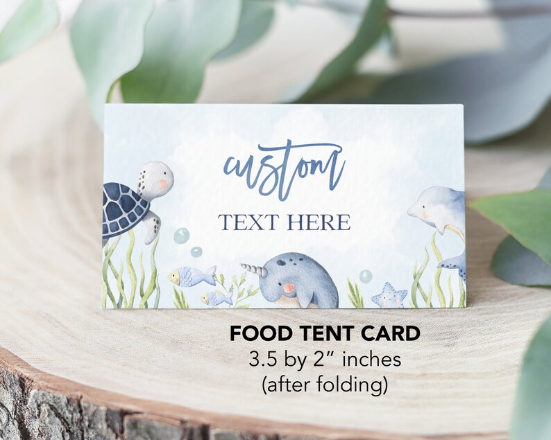 May include: A blue and white food tent card with a watercolor illustration of a turtle, narwhal, and dolphin. The text "custom TEXT HERE" is printed on the card. The card measures 3.5 by 2 inches when folded.