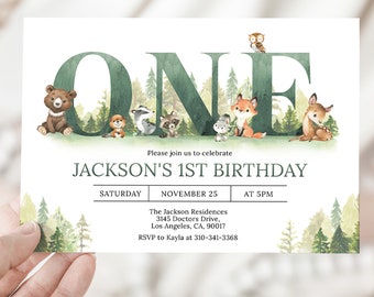 May include: A woodland-themed first birthday invitation with a watercolor illustration of the word "ONE" surrounded by forest animals. The invitation includes the name "JACKSON'S 1ST BIRTHDAY", the date "SATURDAY, NOVEMBER 25", the time "AT 5PM", the location "The Jackson Residences, 3145 Doctors Drive, Los Angeles, CA, 90017", and the RSVP information "RSVP to Kayla at 310-341-3368".