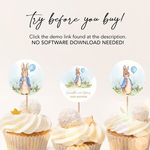 May include: Three white cupcakes with blue and white Peter Rabbit themed cupcake toppers. The toppers feature a watercolor illustration of Peter Rabbit holding a blue balloon. The middle cupcake topper also includes the text "Samantha and Aiden Baby Shower".