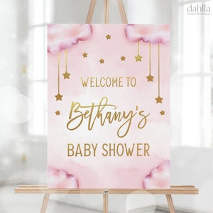 Może przedstawiać: R&oacute;żowo-złoty napis powitalny na baby shower z chmurami i gwiazdami. Napis brzmi "Witamy na baby shower Bethany".