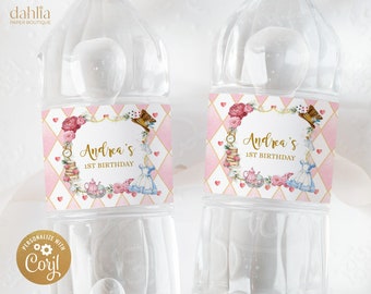Könnte beinhalten: Zwei durchsichtige Plastikwasserflaschen mit rosa und goldenen Etiketten. Die Etiketten zeigen ein fantasievolles Alice-im-Wunderland-Motiv mit Illustrationen von Spielkarten, Teetassen und einer Uhr. Der Text auf den Etiketten lautet "Andrea's 1st Birthday".