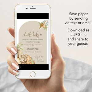 May include: A smartphone displays a baby shower invitation with a dinosaur theme. The invitation features the text "hello baby" and event details. The phone also displays text that says "Save paper by sending via text or email! Download as a JPG file and share to your guests!"