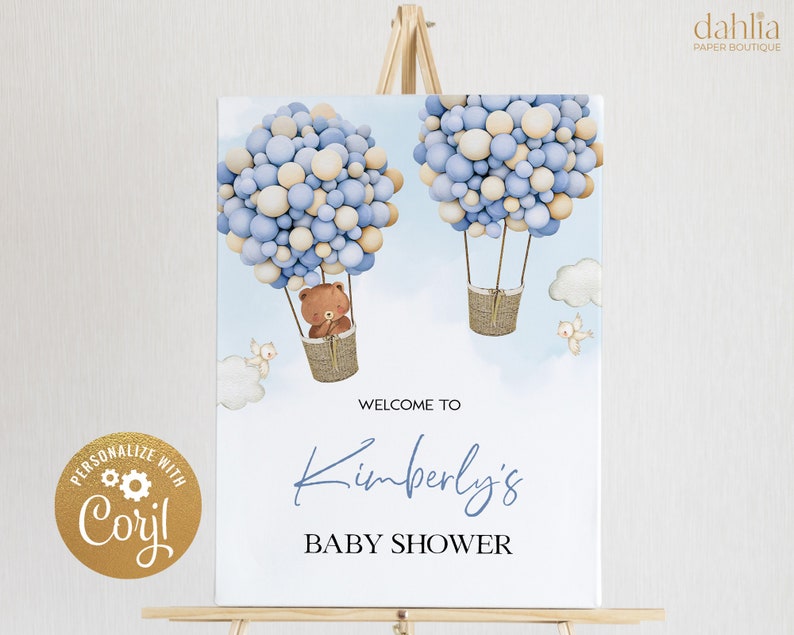 K&ouml;nnte beinhalten: Willkommen zur Babyparty von Kimberly Schild mit einem blauen und beigefarbenen Ballon-Hei&szlig;luftballon mit einem Teddyb&auml;ren im Korb. Das Schild steht auf einem Holzst&auml;nder.